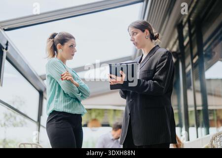 Business collaboration and discussion between two professional women in a modern office setting Stock Photo
