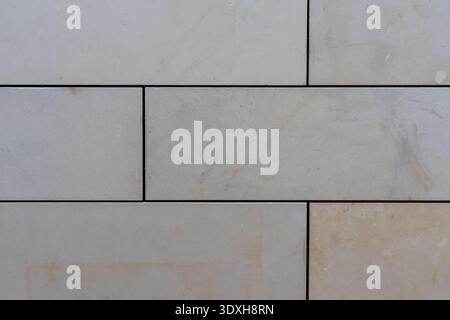 Full frame background texture of a smooth light grey stone tile wall with dark horizontal and vertical grout lines. Stock Photo