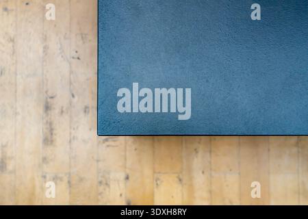 Top down view of a dark blue textured rectangular podium edge resting on a light scratched wooden floor with copy space. Stock Photo