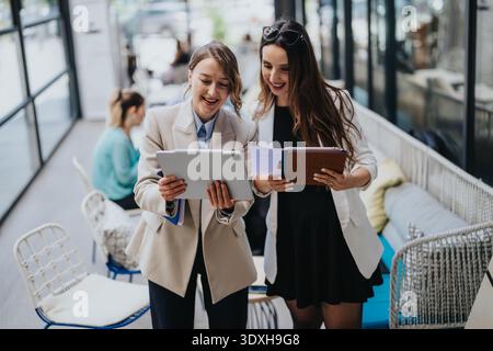 Two businesswomen collaborating over a tablet and documents in a modern co working lounge Stock Photo