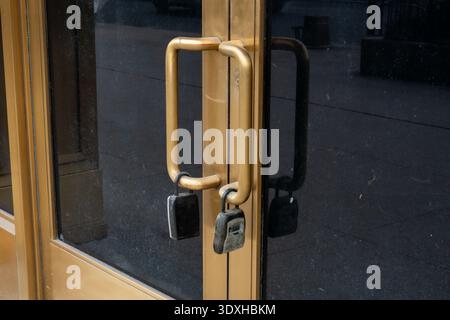 Modern entrance with golden-framed glass doors featuring black glass and code locks on handles entrance with black glass doors Stock Photo