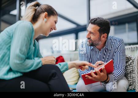 Business collaboration between two colleagues discussing notes during a casual office meeting Stock Photo