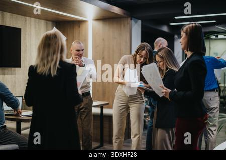 Group of professionals collaborating in a modern office, reviewing documents and discussing projects Stock Photo