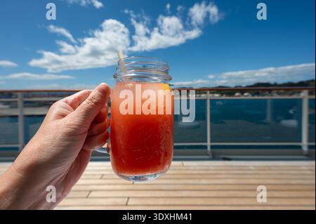 Glass of Fresh Grapefruit Juice in Hand. Refreshing Beverage on Cruise Vacation. Stock Photo