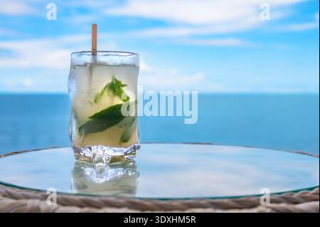Refreshing Cocktail with Mint Leaves and Lime Served by the Seaside. Summer Drink and Relaxation Concept. Stock Photo