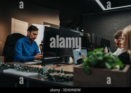 Professional office scene with developers at desks, computers, and monitors working on a project together Stock Photo