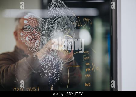 Person writes on glass board in an indoor office, capturing ideas and planning a business project Stock Photo