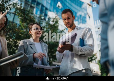 Business colleagues discuss documents outdoors on a sunny spring day in the city Stock Photo