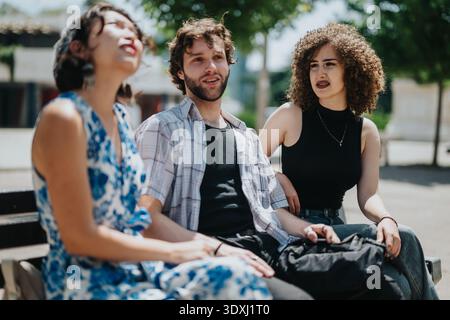 Three friends sit on a sunny park bench, chatting and relaxing outdoors Stock Photo
