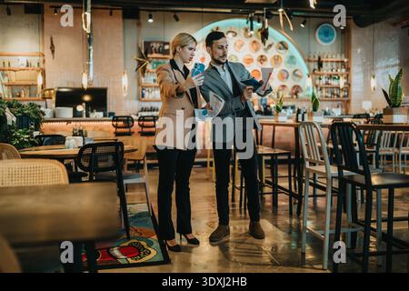 Business partners review documents in a modern cafe setting during a casual meeting Stock Photo