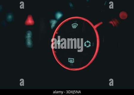 Close-up of illuminated car dashboard climate control knob with red light glow in a dark modern vehicle interior Stock Photo