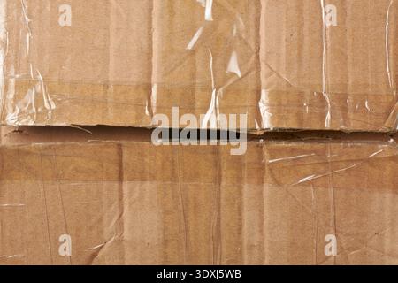 opened brown corrugated cardboard box with clear adhesive tape, slightly open flaps showing dark gap, top view in closeup, shipping and unboxing Stock Photo