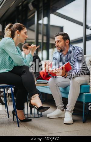 Two professionals in a focused business collaboration discussing notes during a casual office meeting Stock Photo