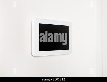 Smart home tablet on wall. Smart home technology device in modern home. Digital remote control system for air conditioning, security system or house a Stock Photo