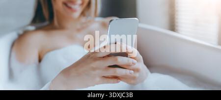 Woman Relaxing in Bathtub While Using Smartphone During Daytime Stock Photo