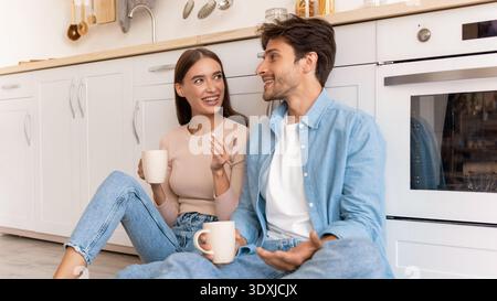Couple Enjoys Conversation and Coffee in Modern Kitchen on a Sunny Morning Stock Photo