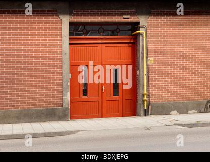 Large industrial red wooden gate on a red brick wall building. Stock Photo