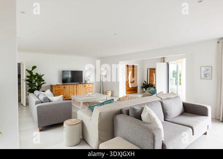 Two grey sofas are facing white coffee table in bright living room near glass doors Stock Photo