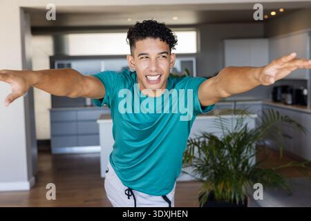 African American man balancing and posing while leaning forward in kitchen near island and plant Stock Photo