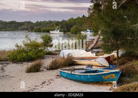 Abandoned boats on sandy beach at high tide, Tin Can Bay, Queensland Australia Stock Photo