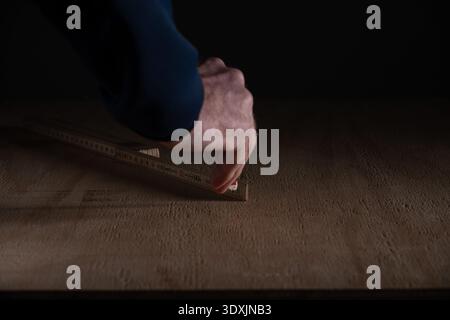 Close up of hand measuring wooden floor using folding ruler. Concept of home renovation, carpentry work, DIY project and interior construction prepara Stock Photo