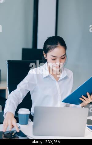 Charming smiling adult woman middle aged woman with curly hair architect designer working on computer in the bright modern office Stock Photo