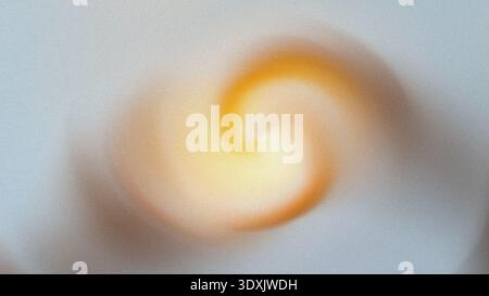 A blurred abstract swirl of yellow and orange light against a soft white background creating a vortex effect Stock Photo