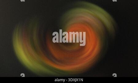 Abstract blurred swirl of colors with orange yellow and green hues against a dark background creating movement Stock Photo