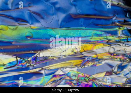 Vibrant iridescent refraction on a folded film microscopic spectrum surface with blue tones Stock Photo