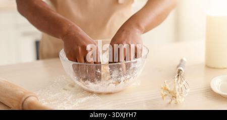 Person Mixes Dough in a Clear Bowl in Kitchen While Preparing for Baking Session Stock Photo
