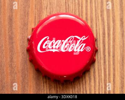 Yerevan, Armenia - January 18, 2026: above view of red tin cap from Coca-Cola bottle closeup on wooden board background Stock Photo
