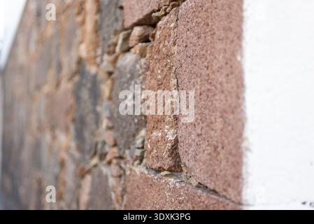 Close-up of a rustic stone wall with roughly hewn stones in reddish-brown tones. Angled view. Stock Photo