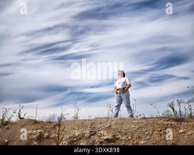 Woman enjoying a scenic view during her travel adventure in nature with beautiful clouds in the background Stock Photo