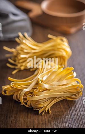 Strands of fettuccine pasta rest on a white surface, appearing soft and fresh. This type of pasta is often used in various dishes. Stock Photo