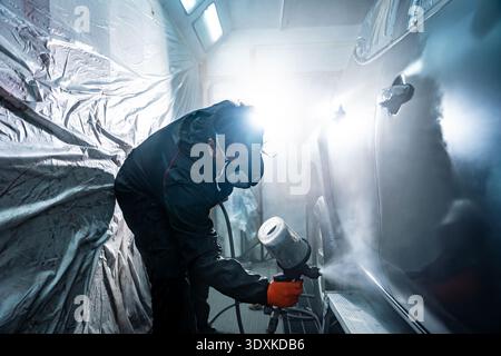 Auto body painter using spray gun in repair shop Stock Photo