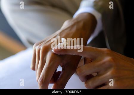 Adult woman applying white cream on back of hand at home, showing cuff and jacket Stock Photo