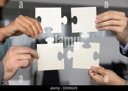 Hands of diverse business partners join puzzle elements together Stock Photo