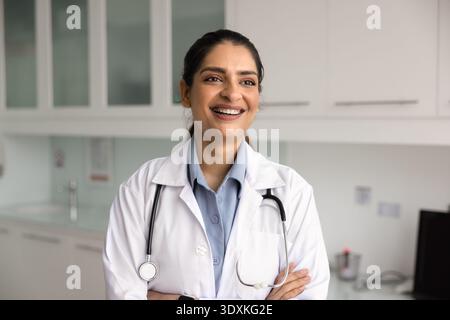 Indian woman doctor in white coat posing in clinic office Stock Photo