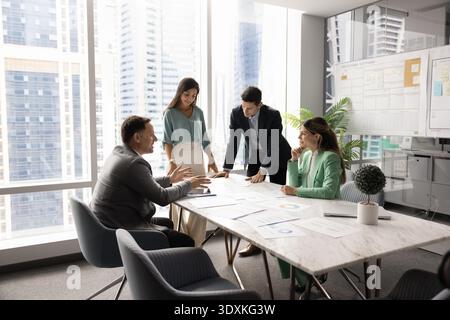Multiethnic startup developers team gather around boardroom table brainstorming insights Stock Photo