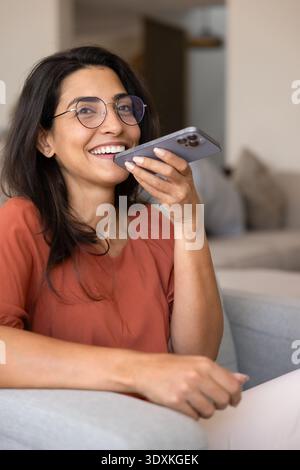 Happy woman using voice assistant on smartphone Stock Photo