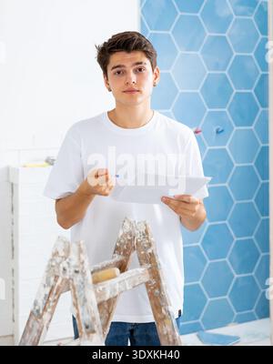 Motivated guy taking notes while working on renovation of house Stock Photo