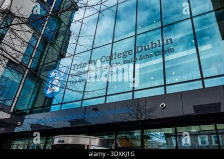 Glass facade of the Trinity Biomedical Sciences Institute, Trinity College Dublin, Ireland, featuring building signage and college crest. Stock Photo