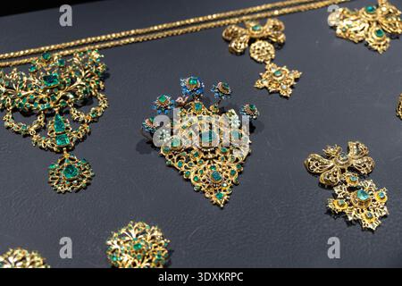 Antequera, Spain 17 Dec 23: Detailed view of historic gold jewelry with green stones and enamel in a museum showcase in Antequera, Andalusia, Spain. Stock Photo
