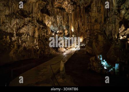 Massive calcite dripstone pillar with textured stalactites and stalagmites under cave lighting in Nerja Cave, Spain. Stock Photo