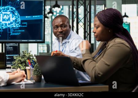 Technicians in AI neural network startup office brainstorming, building scalable solutions for businesses. IT staff members doing meeting to discuss deep learning tech implementation Stock Photo