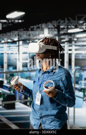 Data center female programmer using virtual reality technology to simulate artificial intelligence neural network systems. Woman in server farm using VR glasses equipment to oversee AI tools. Stock Photo