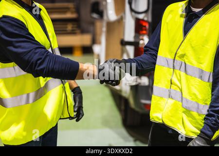 Workers shaking hands for partnership in warehouse Stock Photo