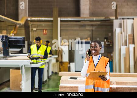 Female manager talking on phone at lumber mill Stock Photo