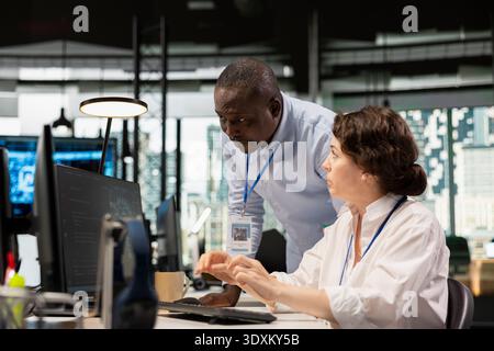 Manager supervising intern in office automating tasks using AI scripts on PC. Silicon Valley startup team leader overseeing employee using deep learning tech to speed up feature implementation Stock Photo