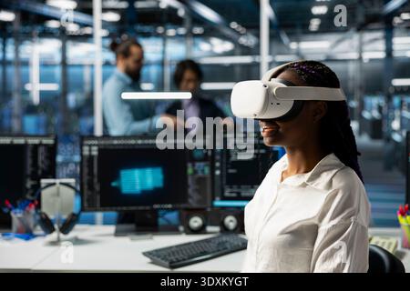 Engineer using virtual reality tech in data center to install upgraded server racks systems with AI. Server room worker wearing VR headset upgrading gear using artificial intelligence Stock Photo